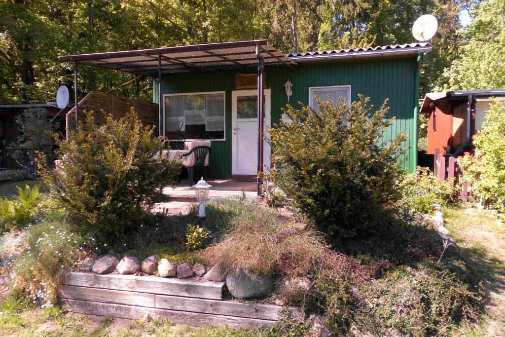 a small green house with a porch and some bushes at Ferienbungalow Fleesensee in Malchow