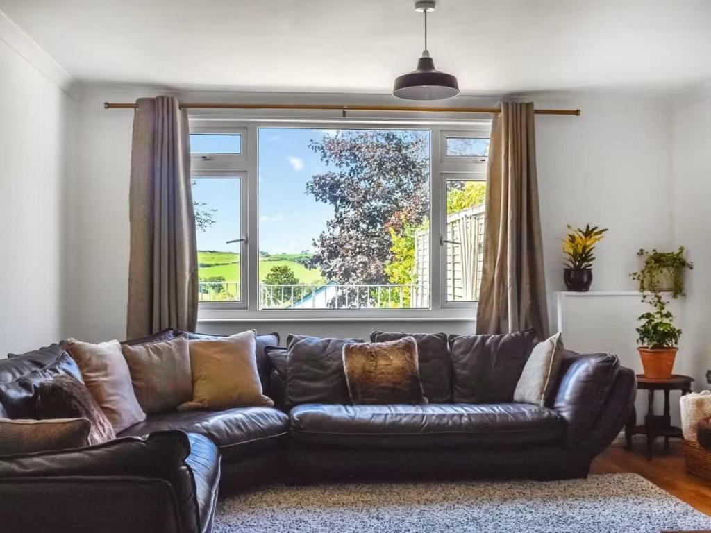 a leather couch in a living room with a large window at The Hideaway - Spacious 3 Bedroom Apartment in Truro