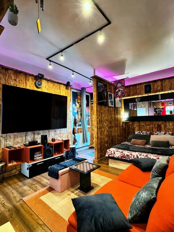 un salon avec un canapé et une télévision à écran plat dans l'établissement Romantic Room - Studio Jardin - Proche Disneyland Paris, à Crécy-la-Chapelle