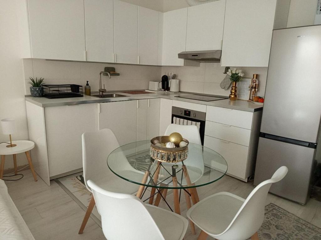 a kitchen with a glass table and white cabinets at Duna Apartment, FreeGarage, 2Room, smartTV,Dishwasher,AC in Budapest