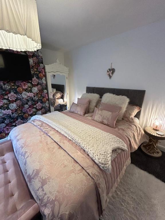 a bedroom with a large bed with pink pillows at Cannons Loft Central Buxton, Duplex loft 3 bedroom Set over 3 floors stairs no lift sleeps 5 in Buxton