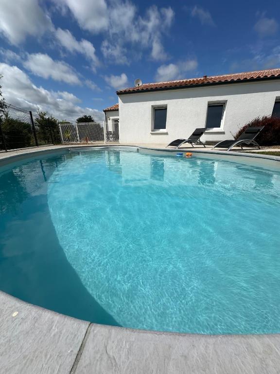 une grande piscine bleue devant une maison dans l'établissement Maison récente avec Piscine à 15' des plages en vélo, à Le Bernard