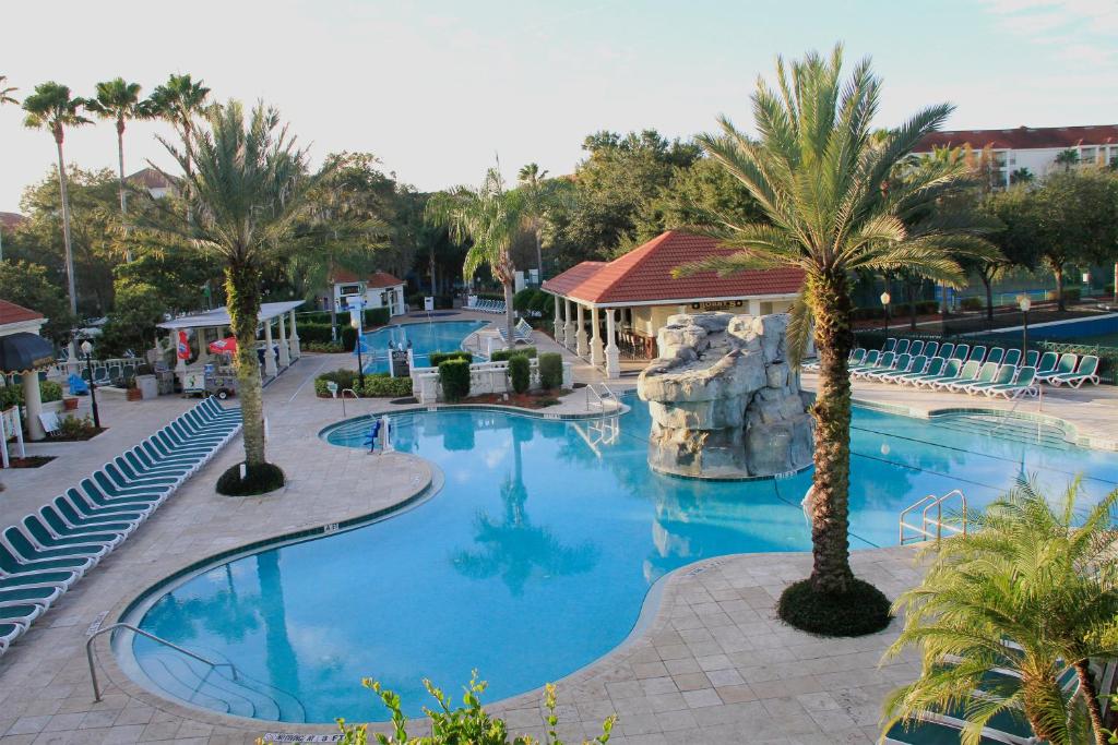 uma piscina num resort com palmeiras e cadeiras em Star Island Resort and Club - Near Disney em Kissimmee