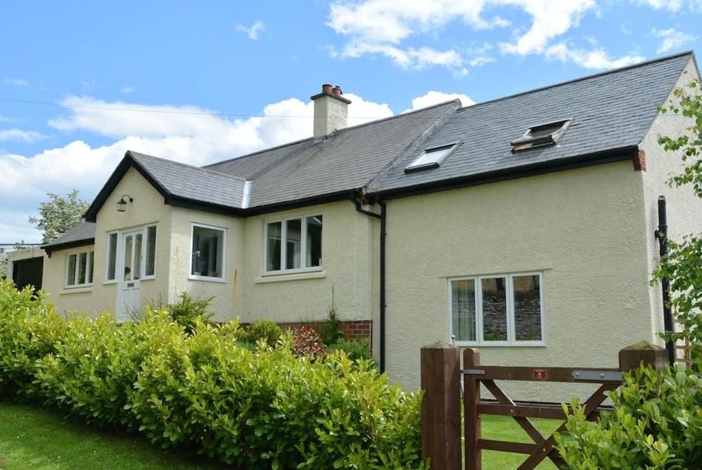 een wit huis met een zwart dak bij Heatherlea Holiday Cottage in Otterburn