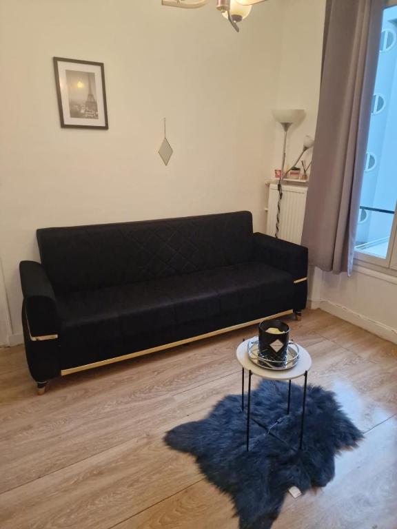 - un canapé noir dans le salon avec une table dans l'établissement Logement 2 pièces très bien situé, proche parc des princes, à Boulogne-Billancourt