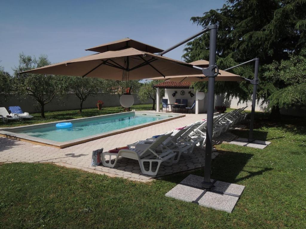 a pool with an umbrella and lounge chairs and a swimming pool at Ferienhaus - Bungalow Lavanda 4 in Poreč
