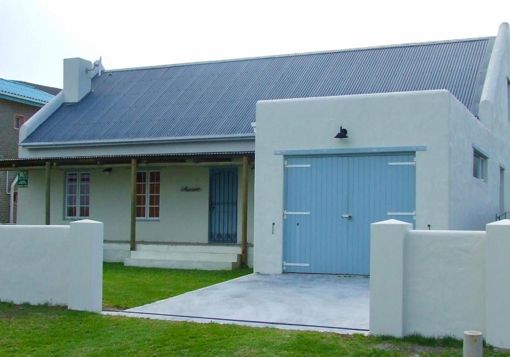 een wit huis met een blauwe garage bij Sea Cottage on Julia in Franskraalstrand