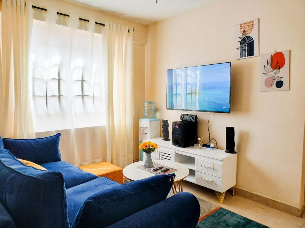 a living room with a blue couch and a tv at Cutie homes_studio in Nairobi