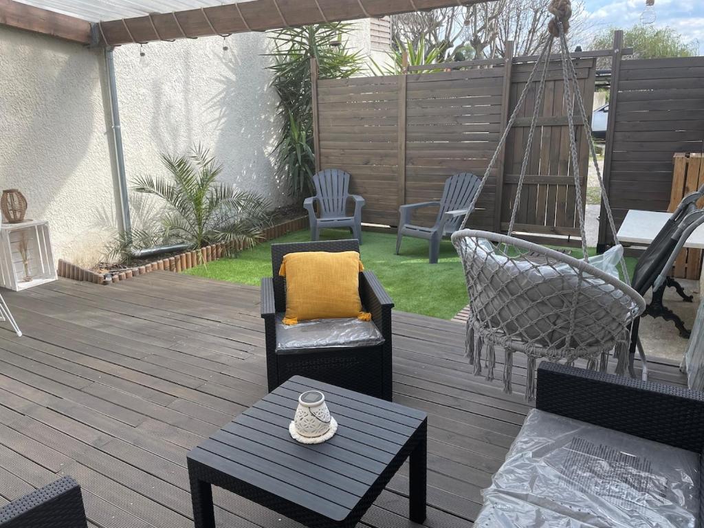 une terrasse en bois avec des chaises et des meubles. dans l'établissement maisonnette adossée a un mas 2 chambres, à Orange
