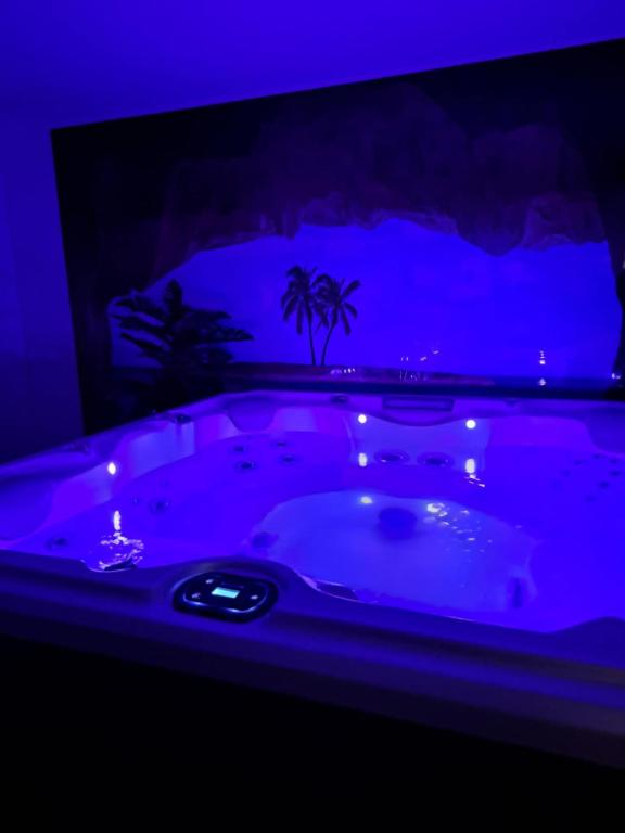 une baignoire jacuzzi dans une chambre avec des lumières bleues dans l'établissement So'Lovely maison entièrement privative avec jacuzzi à 10mn de Caen et 20mn des plages, à Vieux