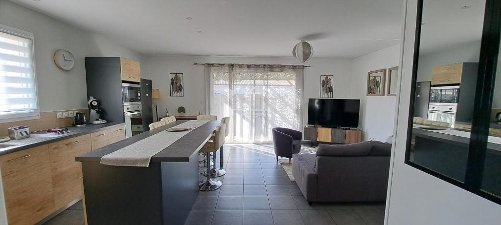 une cuisine avec un comptoir et un salon avec un canapé dans l'établissement Maison 3 chambres, à Parentis-en-Born