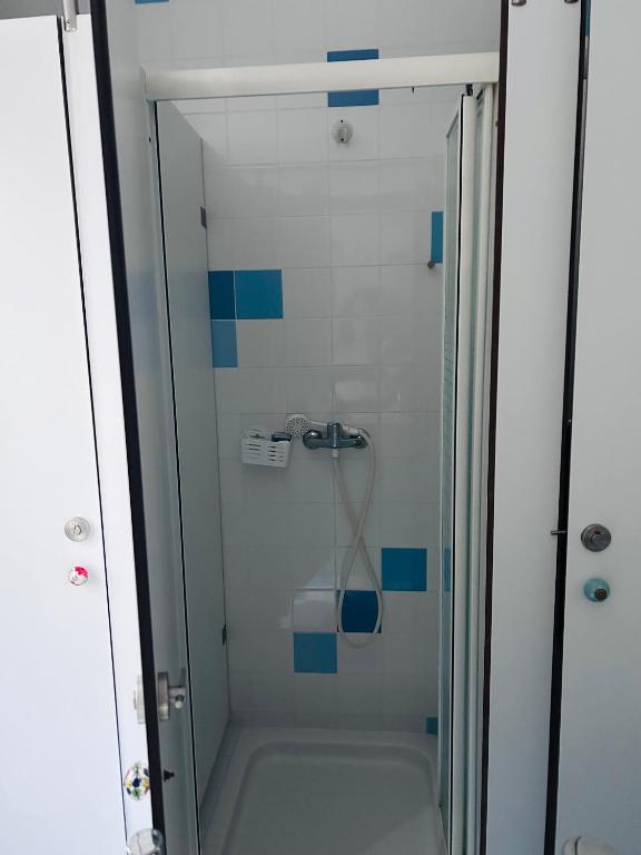 a glass shower with blue tiles in a bathroom at 70's Hostel in Ericeira
