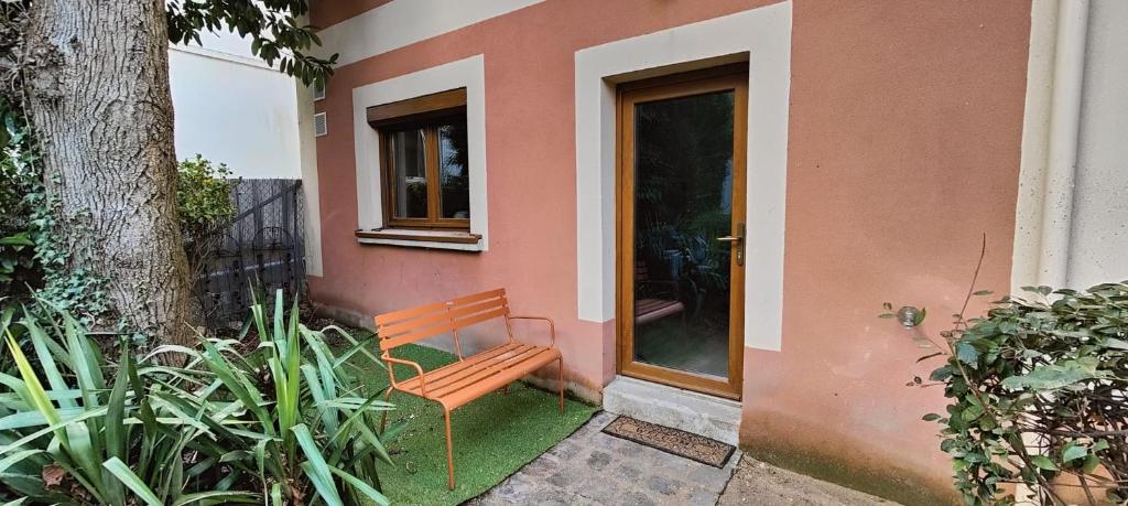 un banc en bois assis à l'extérieur d'une maison dans l'établissement Charmant studio privatif proche Paris et Disneyland, à Thorigny-sur-Marne