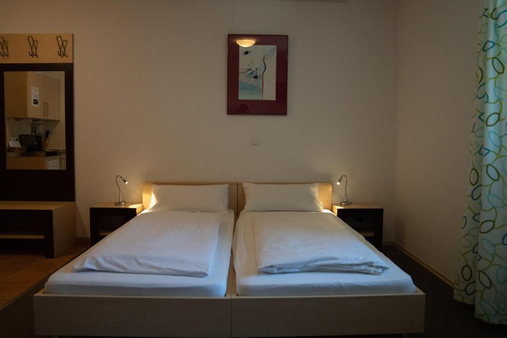a bedroom with two beds and two lights on the wall at Gästehaus Roming in Moosach