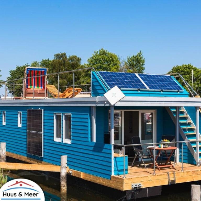a blue tiny house with solar panels on the deck at Hausboot Isa - Huus & Meer in Heiligenhafen