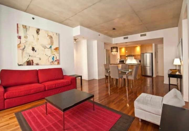 un salon avec un canapé rouge et une cuisine dans l'établissement Chic Downtown Montreal Condo 2 Bed 2 Bath Free Indoor Parking, à Montréal