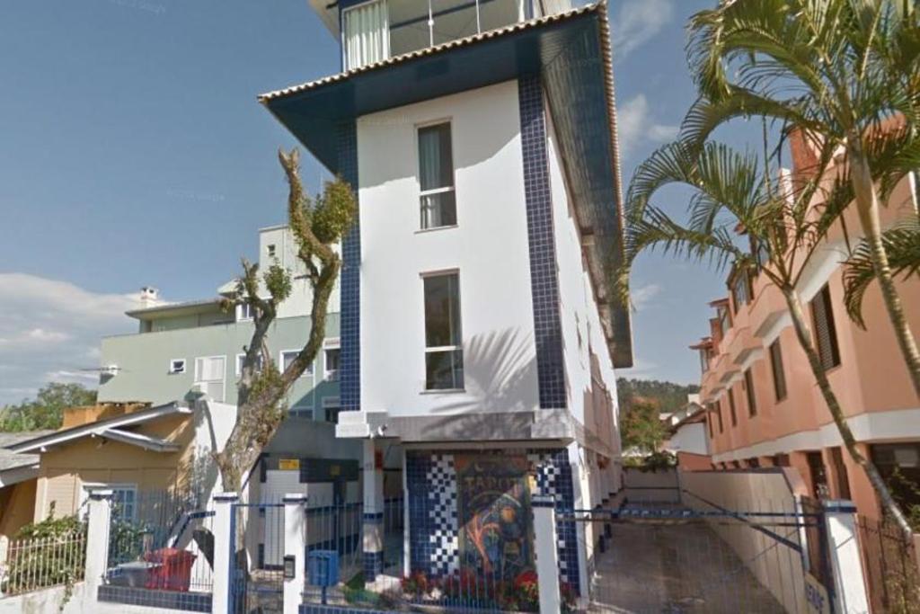 un edificio blanco con palmeras delante en Tarot Residence, en Florianópolis