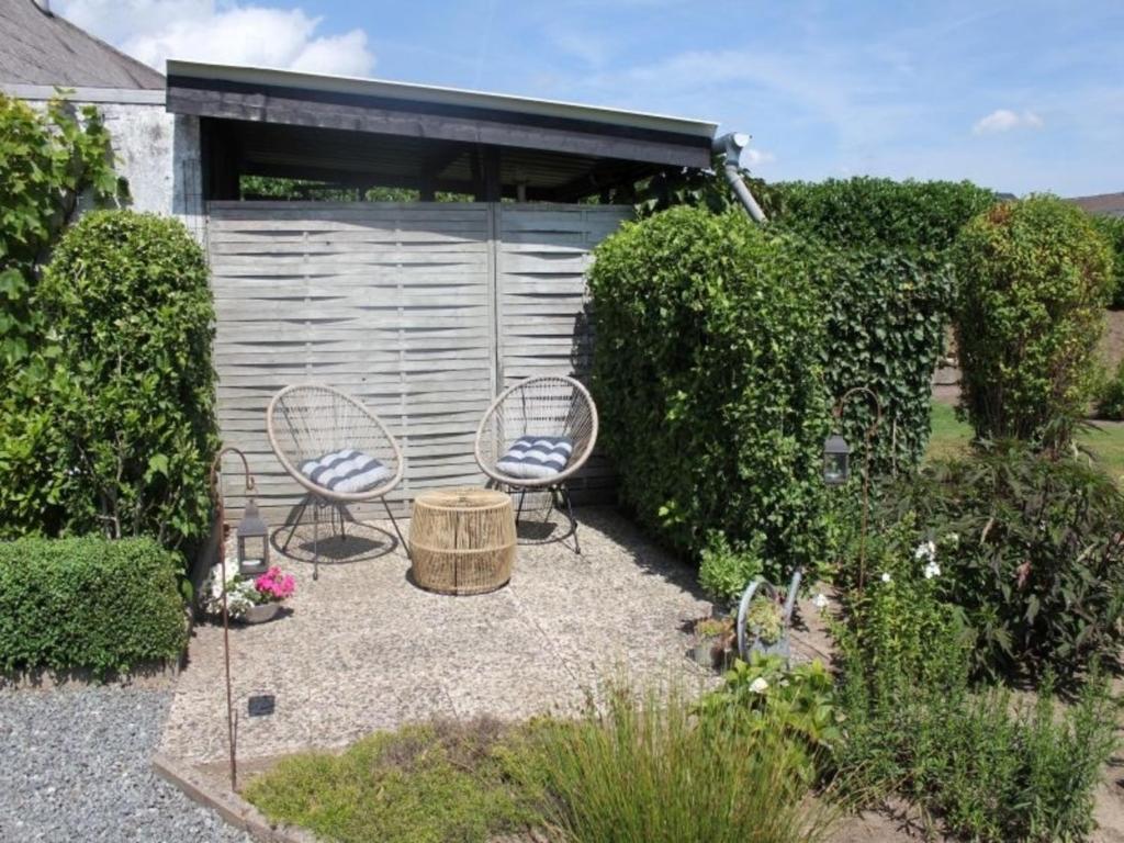 a patio with two chairs and a table in a garden at Dat lütte Ferienhuus an`t Dannewark in Dannewerk