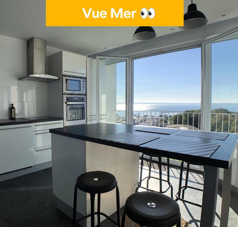une cuisine avec un comptoir avec des tabourets et une grande fenêtre dans l'établissement Superbe appartement avec une vue mer panoramique, à Brest