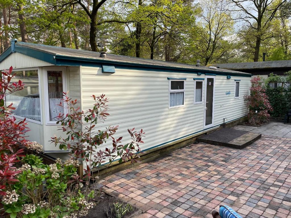 a white tiny house on a brick driveway at Vintage Forest Chalet in IJhorst