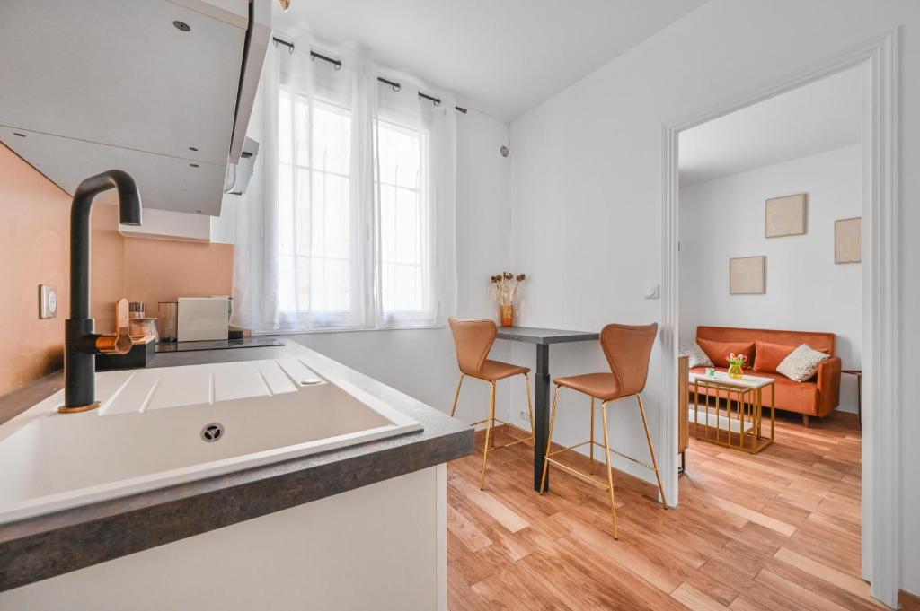 une cuisine avec un évier et une table avec des chaises dans l'établissement Charming appartment marais, à Paris