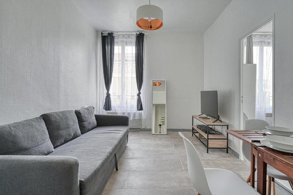 un salon avec un canapé et une télévision dans l'établissement Appartement fonctionnel & lumineux-Portes de Paris, à Argenteuil