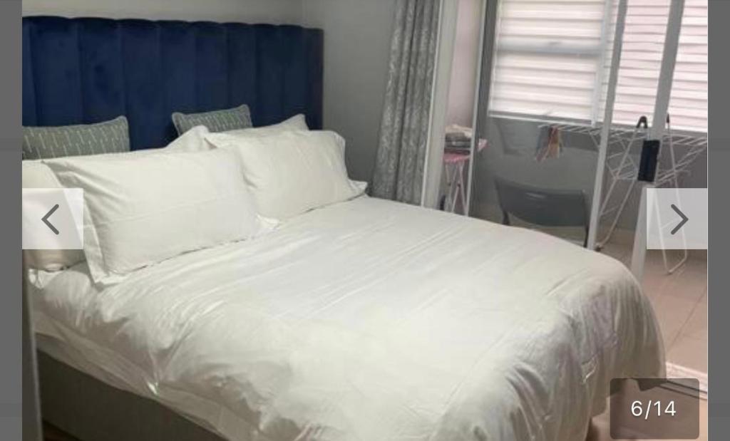 un lit avec des draps blancs et des oreillers dans une chambre dans l'établissement YA Eagle Wings SELF Catering Shared Apartment A, au Cap