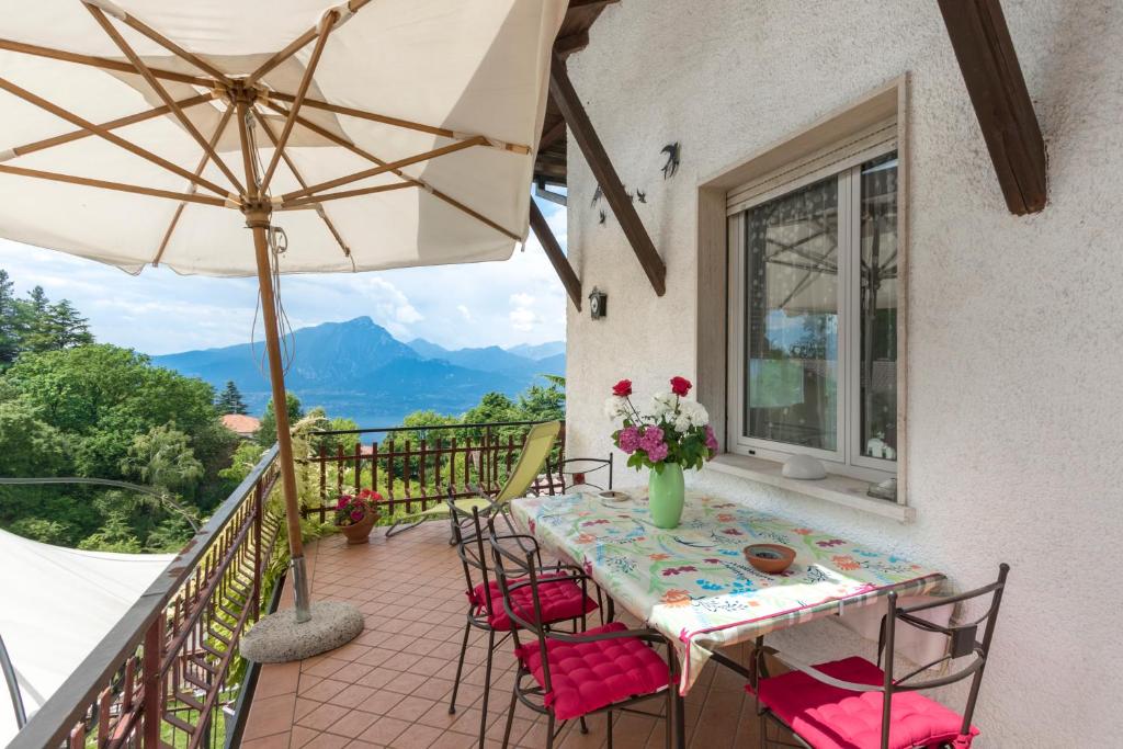 a balcony with a table and chairs and an umbrella at Casa HELI 1 in San Zeno di Montagna