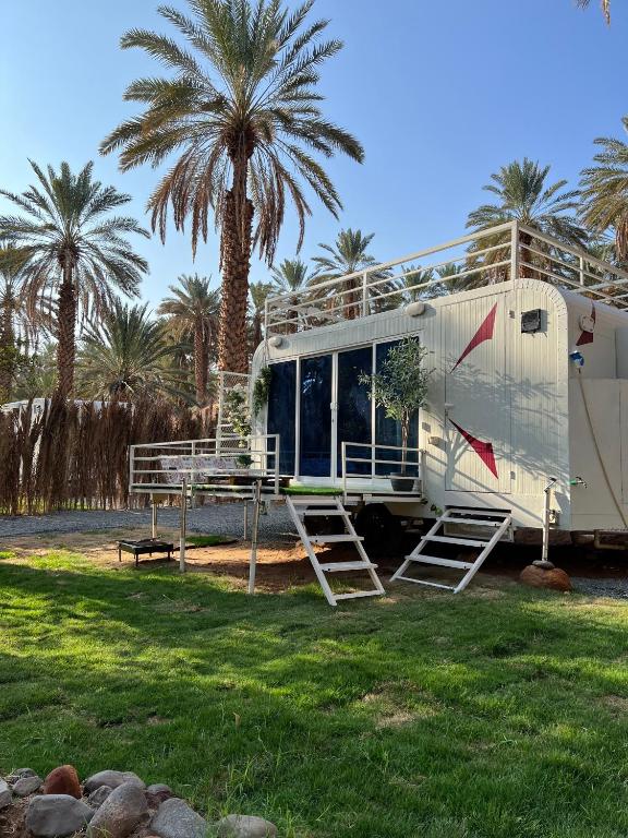 an rv parked in a field with palm trees at كرفان العلا caravan alula in Al-ʿUla