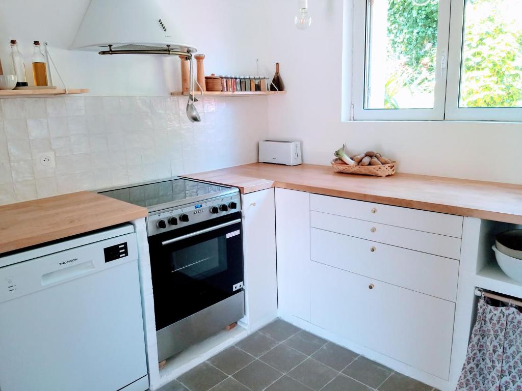 La cuisine est équipée de placards blancs et d'un four avec plaques de cuisson. dans l'établissement Maison avec vue mer à Saint-Pol-de-Léon, à Saint-Pol-de-Léon
