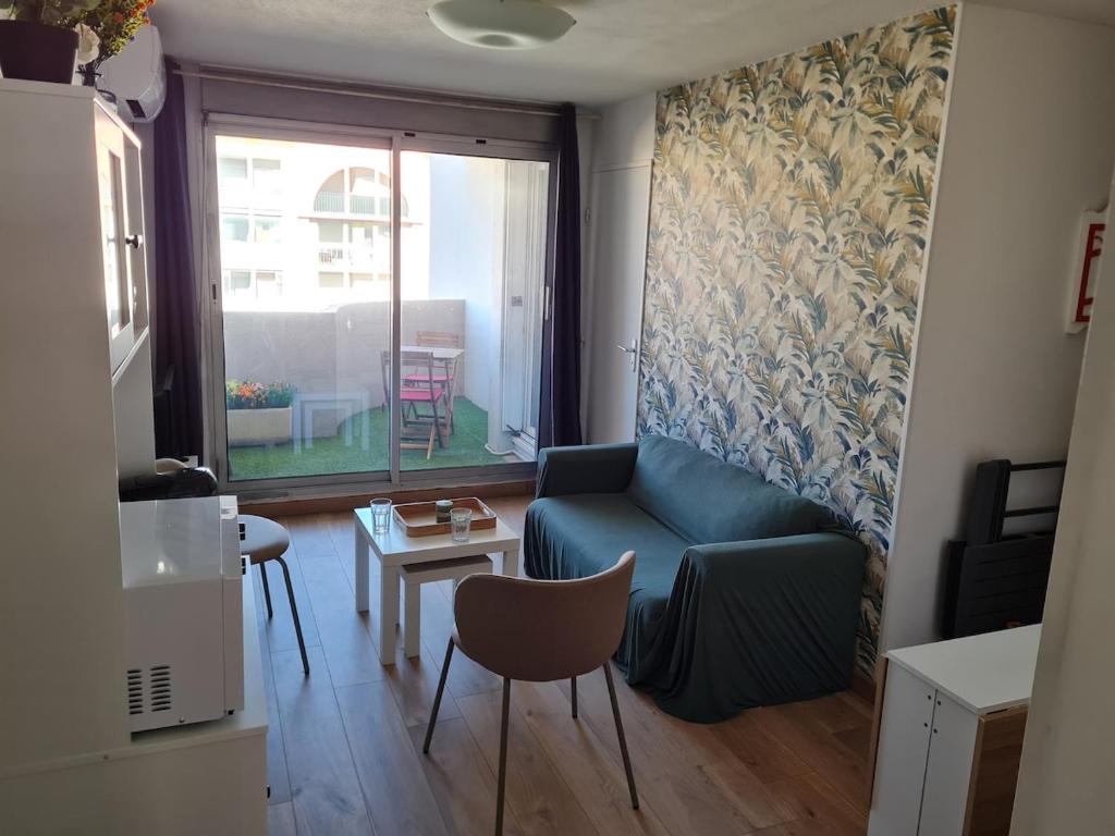 un salon avec un canapé bleu et une table dans l'établissement Appartement T2 proche gare et centre ville, à Sète