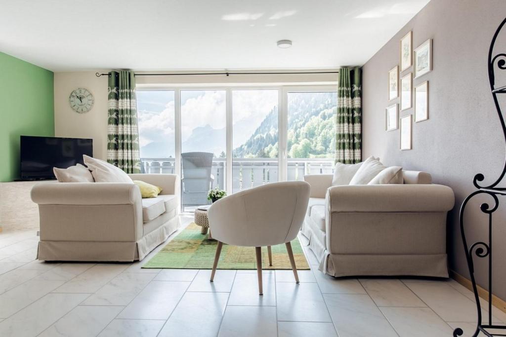 a living room with white furniture and a large window at Wildgrün Panorama Lodge 8b in Pfronten