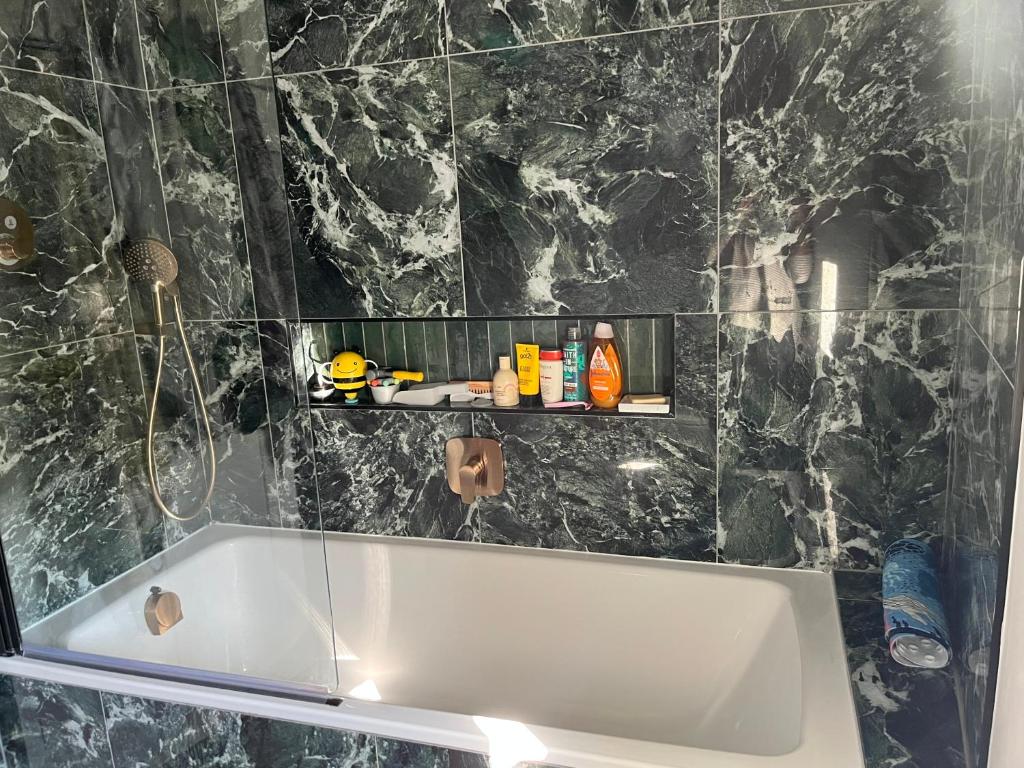 a bath tub in a bathroom with a black marble wall at Charming Home in Central Cambridge in Cambridge