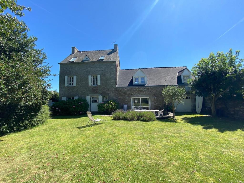 une grande maison avec une chaise dans la cour dans l'établissement Ker Manou St Cast le Guildo 900m des plages et du Golf, à Saint-Cast-le-Guildo