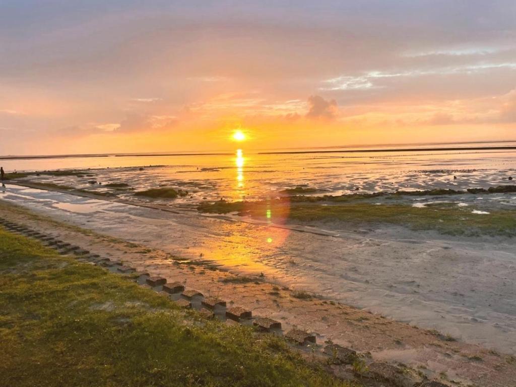 a sunset on a beach with the ocean at Ferienwohnung Zwergpinscher in Dornum