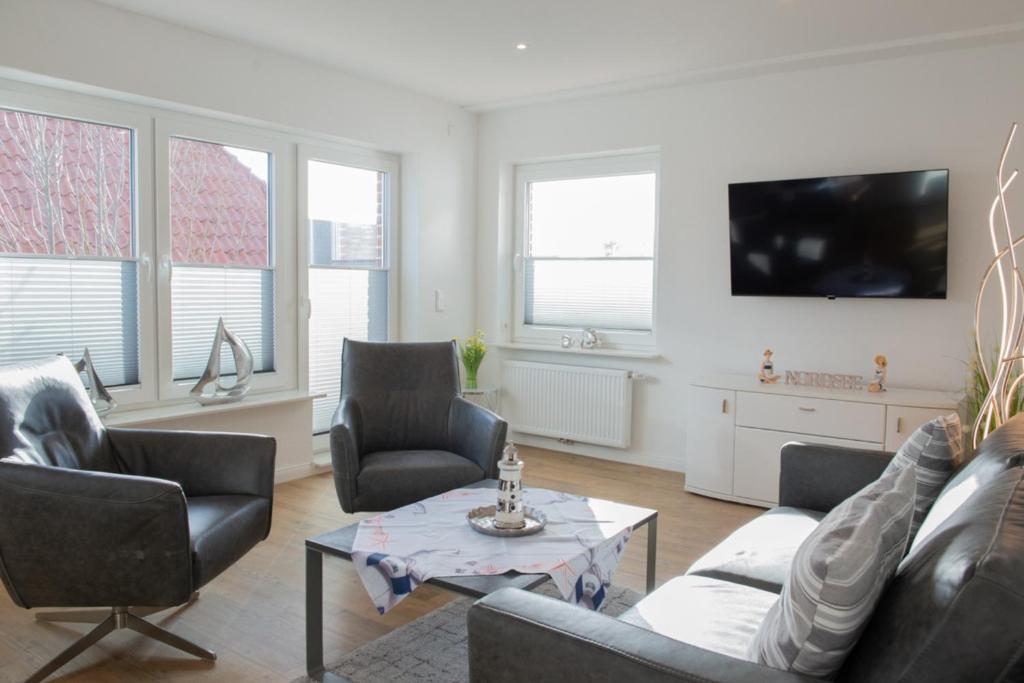 a living room with a couch and chairs and a tv at Mole rechts in Norden