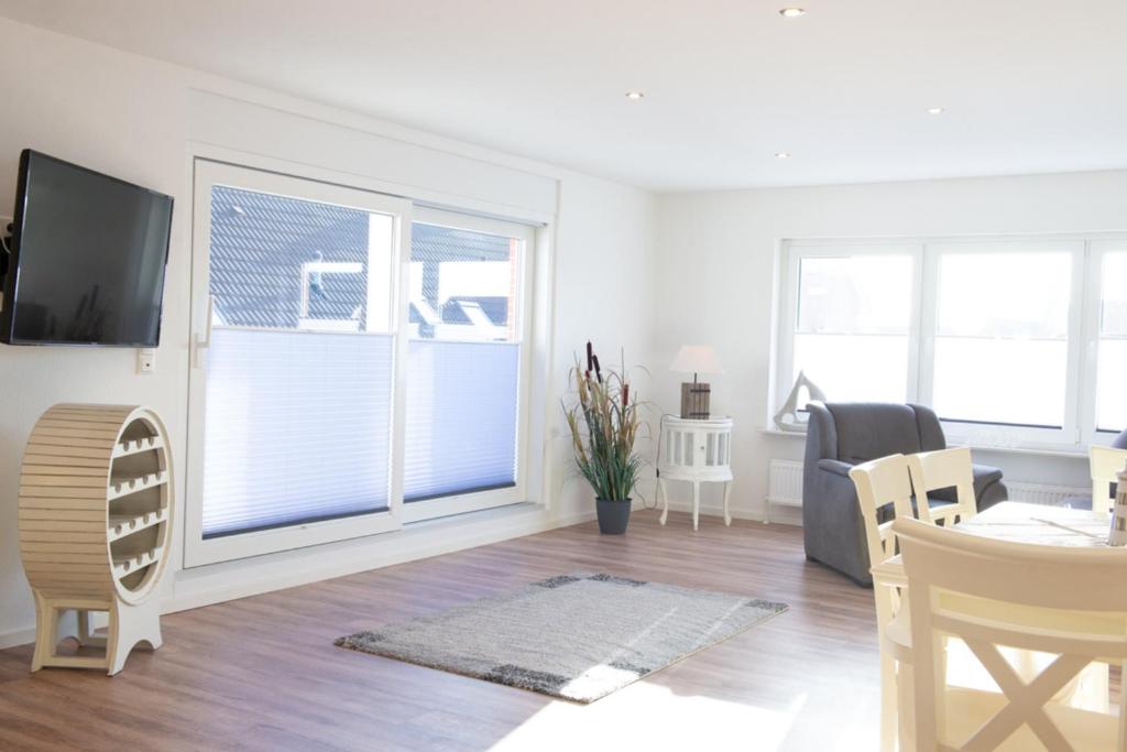 a living room with a tv and a table and chairs at Deichnähe - E in Norden