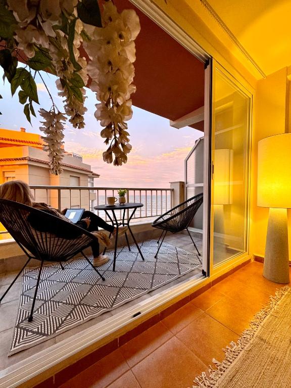 a woman sitting in a chair on a balcony at Casa Palmera in Sueca