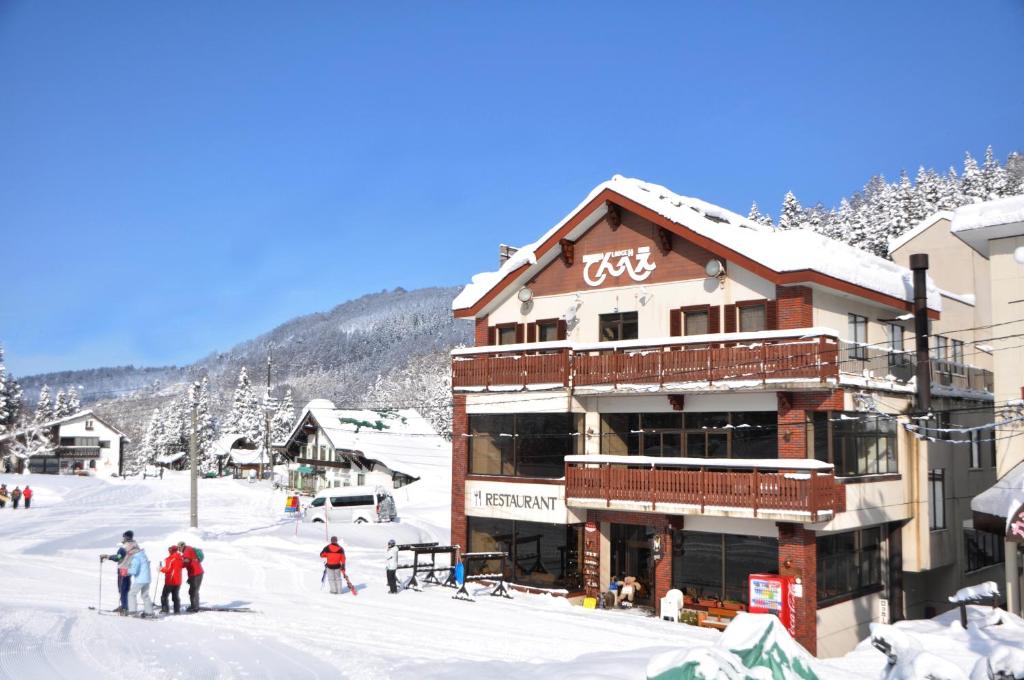 a ski lodge with people standing in the snow at Lodge Denbey in Nozawa Onsen