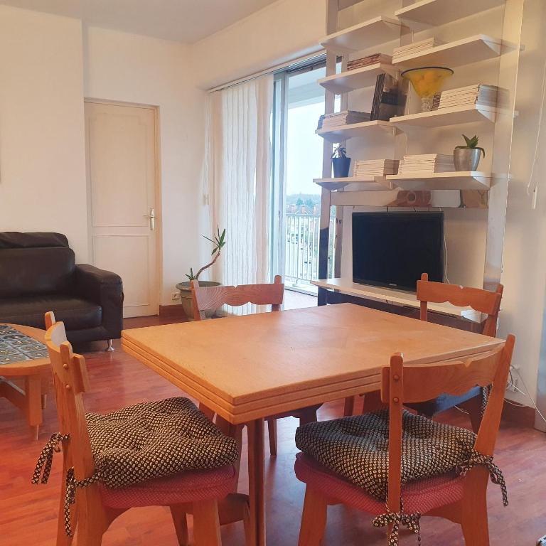un salon avec une table en bois et une télévision dans l'établissement Marq en Baroeul Acacias T2, à Marcq-en-Barœul