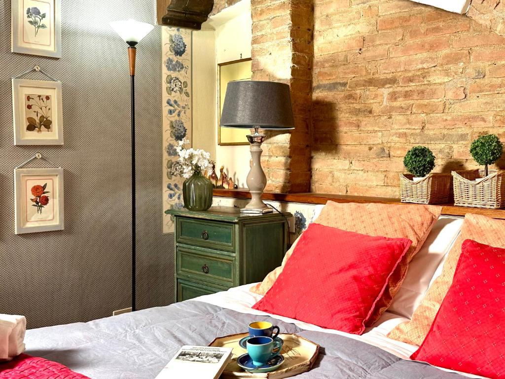 a bedroom with a bed with red pillows and a brick wall at Luxury Deco Painter Ca' Dottori Perugia in Perugia