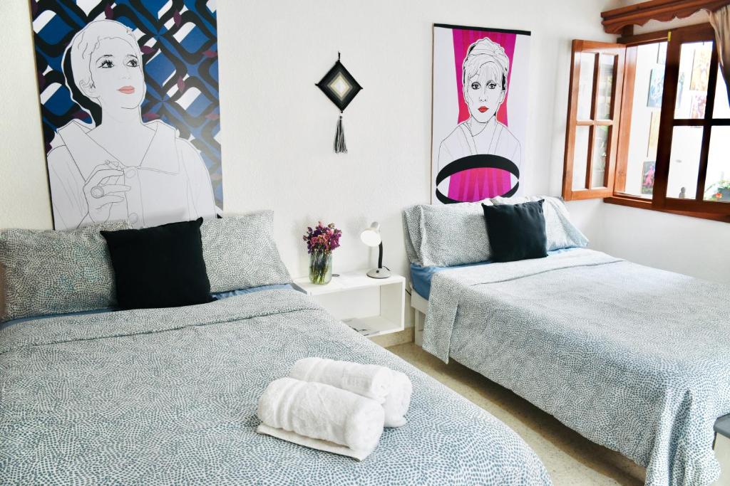 a bedroom with two beds and a painting on the wall at Casa Nazimova Indigo Room in San Cristóbal de Las Casas