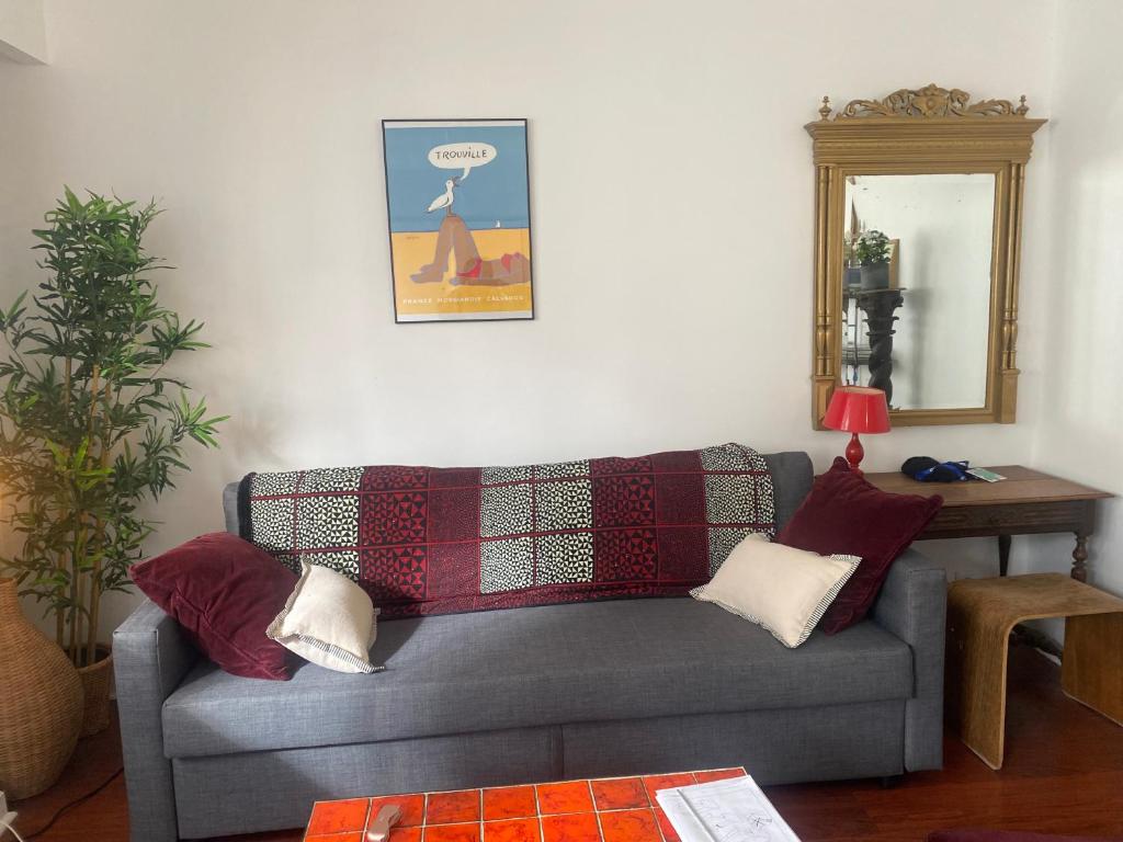 - un salon avec un canapé gris et un miroir dans l'établissement パリ16区 改装したばかりのアパルトマン クーラー付, à Paris