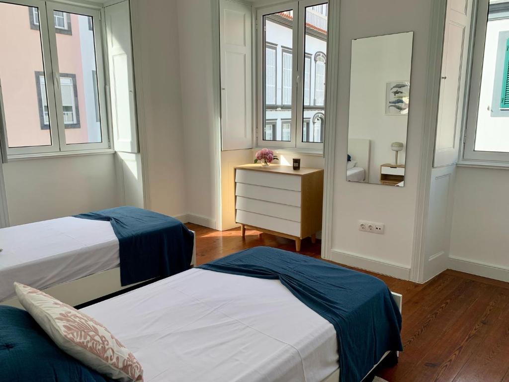 een slaapkamer met 2 bedden, een dressoir en ramen bij Retiro dos Reis in Horta