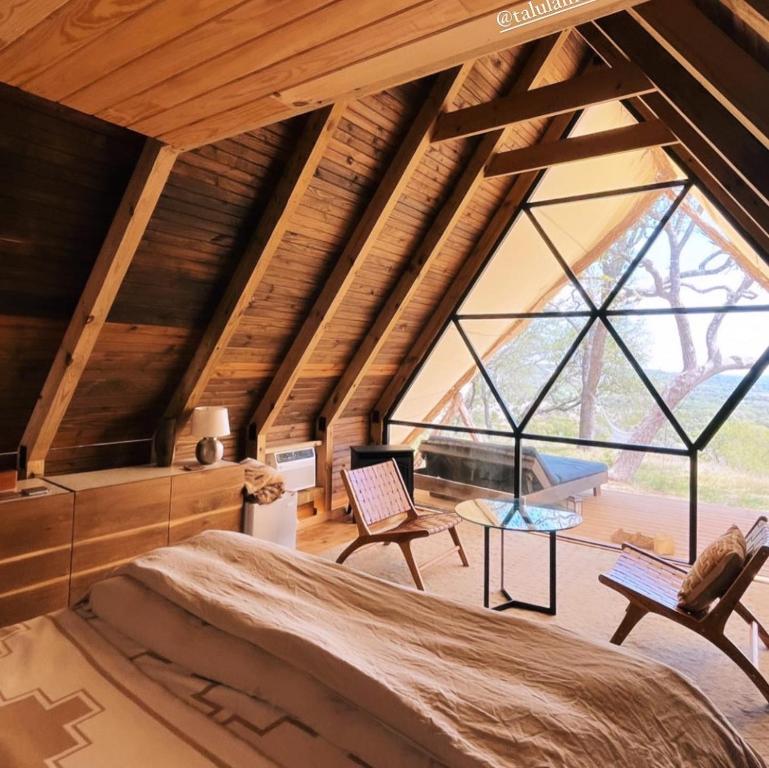 Zimmer mit einem Bett und einem großen Fenster in der Unterkunft Talula Mesa Glamping Resort - Austin Hill Country in Marble Falls