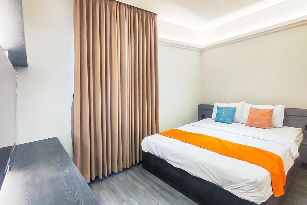 a bedroom with a bed with orange and blue pillows at Sans Hotel Bogor in Bogor