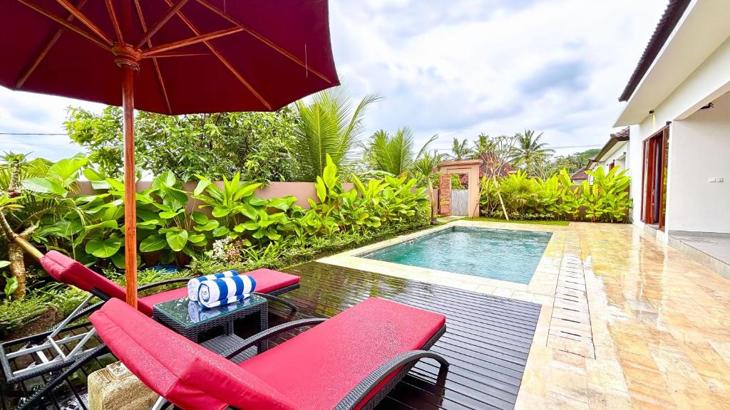 a patio with chairs and an umbrella and a swimming pool at Umah Anyar Villas Ubud in Bedahulu
