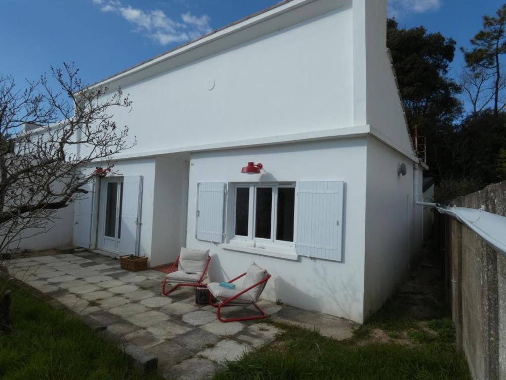 une maison blanche avec 2 chaises sur une terrasse dans l'établissement Maison rénovée à Notre Dame de Monts, 4 pers, proche plage - FR-1-540-317, à Notre-Dame-de-Monts