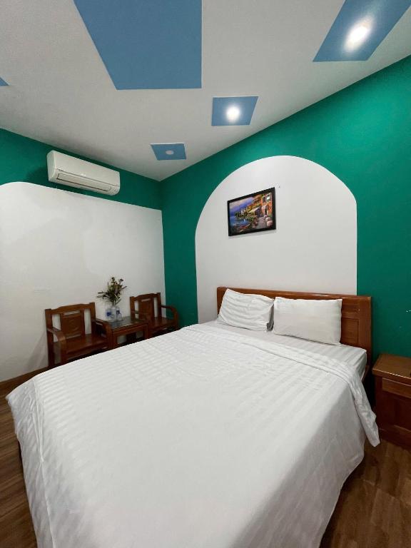 a bedroom with a white bed with a green wall at HomestayHoangYen in Phường Sáu