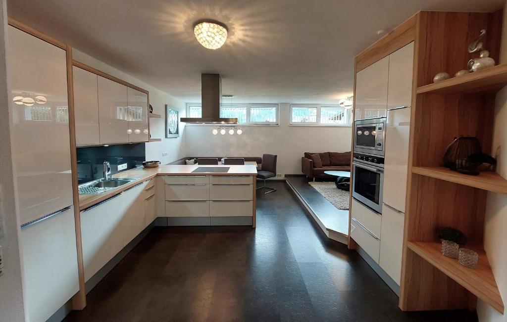 a kitchen with white cabinets and a living room at Ferienwohnung Haag in Schlitters